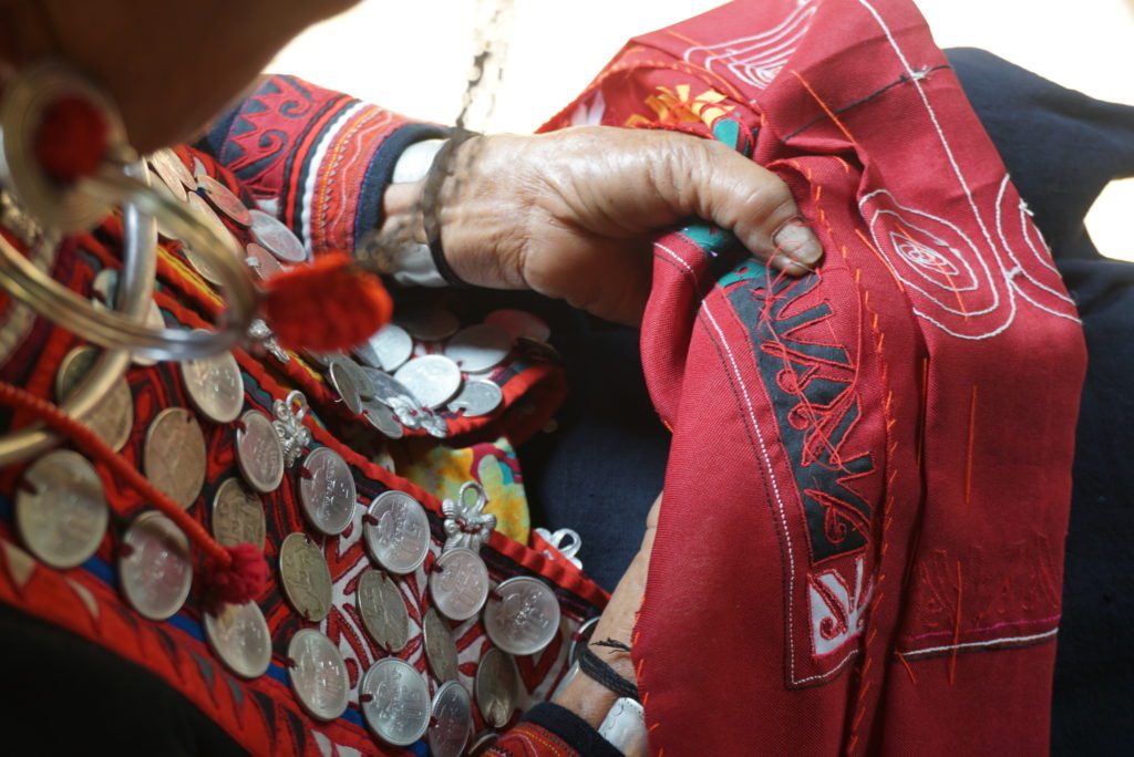 Oma artisan doing embroidery on traditional clothing in Laos