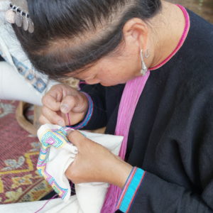 Artisan stitching geometric pattern on tea towel Laos