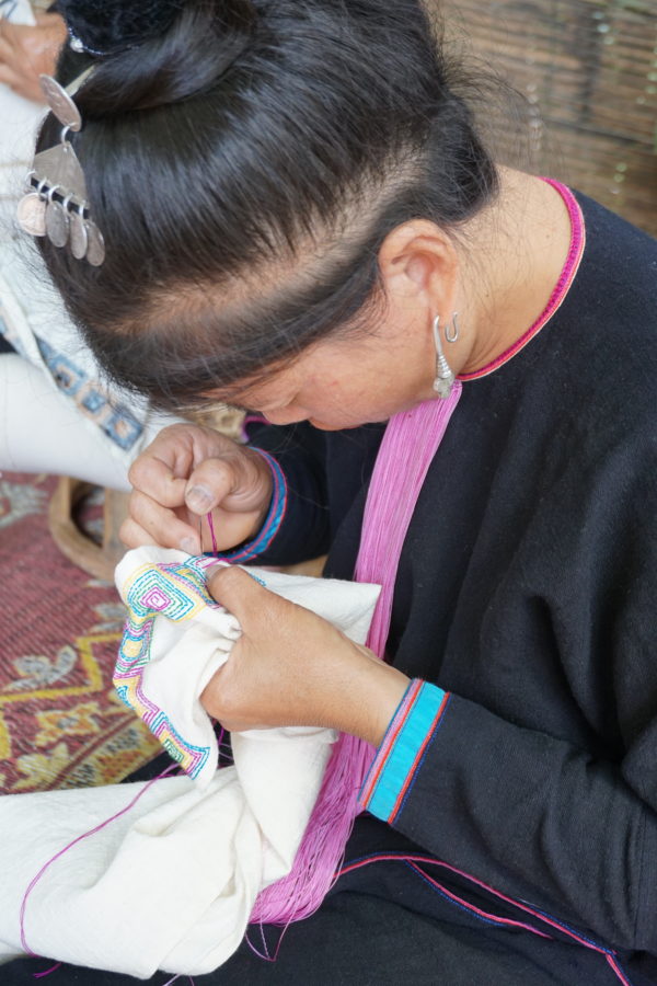 Artisan stitching geometric pattern on tea towel Laos